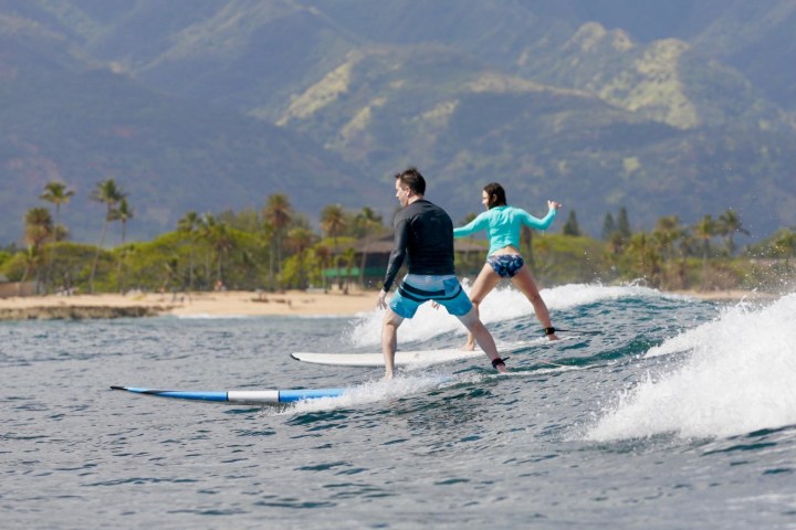 two people riding a wave on a surf lesson in Haleiwa, HI