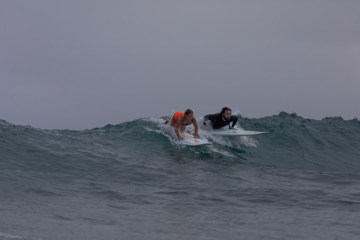 a group of people riding a wave on a surfboard in the ocean